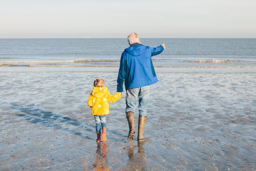 man met kind aan strand